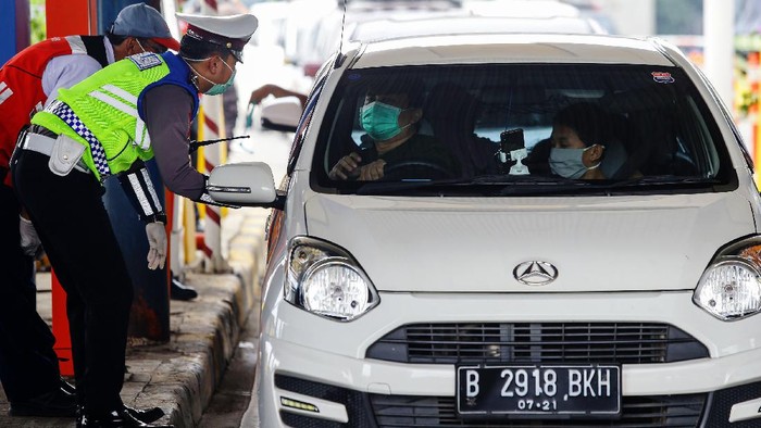 Petugas kepolisian melakukan pengecekan kepada kendaraan yang melintasi gerbang tol Pasar Rebo Utama. Ini bagian dari penerapan PSBB di Jakarta.