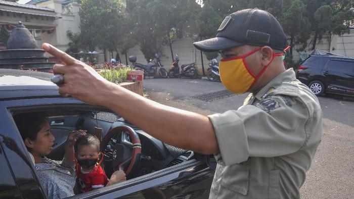 Polisi berjaga di sejumlah perbatasan di DKI Jakarta di hari pertama penerapan Pembatasan Sosial Berskala Besar (PSBB). Polisi mengingatkan warga untuk memakai masker.