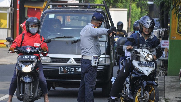 Polisi berjaga di sejumlah perbatasan di DKI Jakarta di hari pertama penerapan Pembatasan Sosial Berskala Besar (PSBB). Polisi mengingatkan warga untuk memakai masker.
