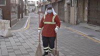 Kamala, seorang pekerja kebersihan setempat berpose untuk potret saat dia menyapu jalan yang sunyi.