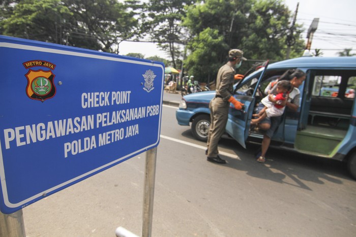 Polisi berjaga di sejumlah perbatasan di DKI Jakarta di hari pertama penerapan Pembatasan Sosial Berskala Besar (PSBB). Polisi mengingatkan warga untuk memakai masker.