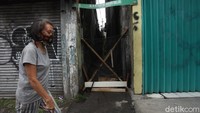 Warga melintas di depan gang K.H Hasyim Ashari dalam, Jakarta yang ditutup menggunakan kayu seadanya.
