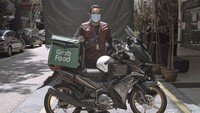 Amirul, seorang pekerja jasa pengiriman makanan berpose untuk potret sambil menunggu pesanan.