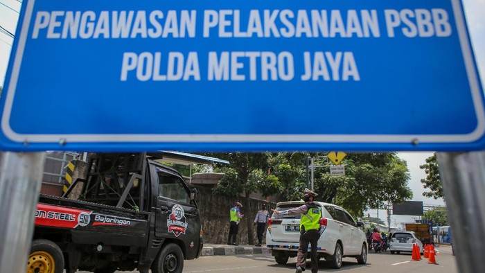 Polisi berjaga di sejumlah perbatasan di DKI Jakarta di hari pertama penerapan Pembatasan Sosial Berskala Besar (PSBB). Polisi mengingatkan warga untuk memakai masker.