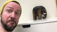 Liburan yang lalu pria ini berfoto dengan kerbau, sekarang hanya bisa berfoto dengan patung gajah.