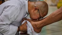 Seorang pendeta Katolik mencium kaki seorang pria tunawisma sebagai bagian dari ritual Kamis Putih. Ezra Acayan/Getty Images.