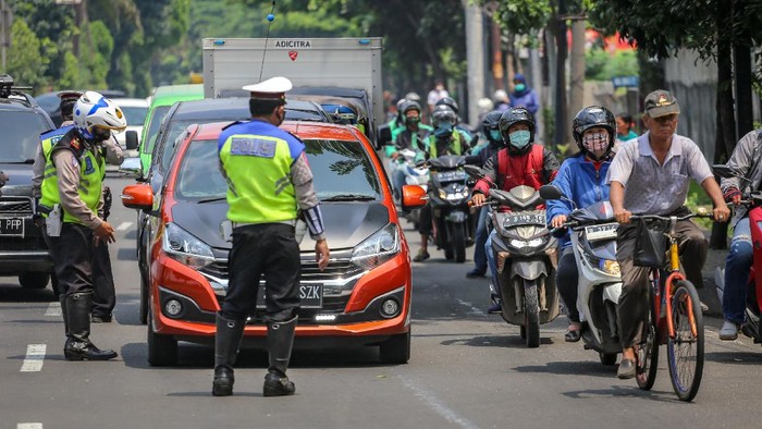 Polisi berjaga di sejumlah perbatasan di DKI Jakarta di hari pertama penerapan Pembatasan Sosial Berskala Besar (PSBB). Polisi mengingatkan warga untuk memakai masker.