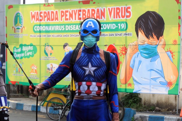 Sejumlah petugas kepolisian yng berpakaian superhero menyemprotkan cairan disinfektan di jalan Panglima Sudirman kawasan Kebonagung, Pasuruan, Jawa Timur, Kamis (9/4/2020). Penyemprotan cairan disinfektan tersebut bertujuan untuk mengantisipasi penyebaran Virus Corona (COVID-19). ANTARA FOTO/Umarul Faruq/aww.