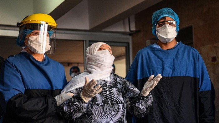 Medical staff cheer as Alye Gunduz (C), 93 years old, who was treated for Covid-19 (novel coronavirus) is escorted to be discharged from the Istanbul University Cerrahpasa medical faculty Hospital after ten days of treatment on April 10, 2020 in Istanbul. - The Cerrahpasa Medical Faculty has responded fast since the outbreak in mid March, turning its operating theatres into intensive care units and creating special pandemic sections separating ordinary patients from others infected with coronavirus -- where entries and exists to and from which are prohibited. (Photo by Ozan KOSE / AFP)