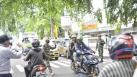 Polisi memberikan masker kepada pengendara sepeda motor saat penerapan penerapan Pembatasan Sosial Berskala Besar (PSBB).