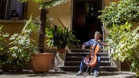 Dua orang musisi tampak memainkan alat musik di pekarangan apartemen mereka yang berada di kawasan Milan, Italia, akhir pekan lalu.  