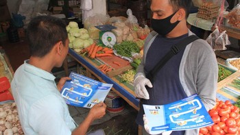 Petugas membagikan brosur sambil mengedukasi pedagang untuk menerapkan belanja melalui media daring di Pasar Bina Usaha, Meulaboh, Aceh Barat, Aceh. Antara Foto/Syifa Yulinnas.