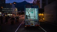 Seorang pria tengah memainkan piano di dalam sebuah truk yang dirombak menjadi tempat les piano keliling di Hong Kong.