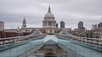 Seorang fotografer memotret kawasan Millennium Bridge atau Jembatan Millenium yang berada di kawasan London, pada 30 Maret 2020 lalu. Suasana kawasan yang sepi dari aktivitas warga itu tampak berbeda dengan foto di bawahnya yang diabadikan pada tahun 2015 silam, dimana terlihat warga wara-wari di kawasan tersebut. Leon Neal/Getty Images, Peter Macdiarmid/Getty Images.