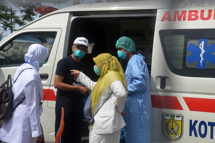 Seorang pasien positif COVID-19 (kedua kiri) yang dinyatakan sembuh bersiap menaiki mobil ambulan saat pemulangan  di Rumah Sakit Zainal Abidin, Banda Aceh, Senin, 13/4/2020). Tim Gugus Tugas Percepatan Penanganan COVID-19 Aceh menyatakan hingga saat ini tercatat sebanyak lima pasien yang sebelumnya dinyatakan positif COVID-19, empat orang  di antaranya sembuh sudah dipulangkan dan seorang pasien lainnya meninggal, sedangkan Pasien Dalam Pengawasan (PDP) sebanyak 60 orang masih dirawat di sejumlah rumah sakit provinsi Aceh. ANTARA FOTO/Ampelsa/hp.