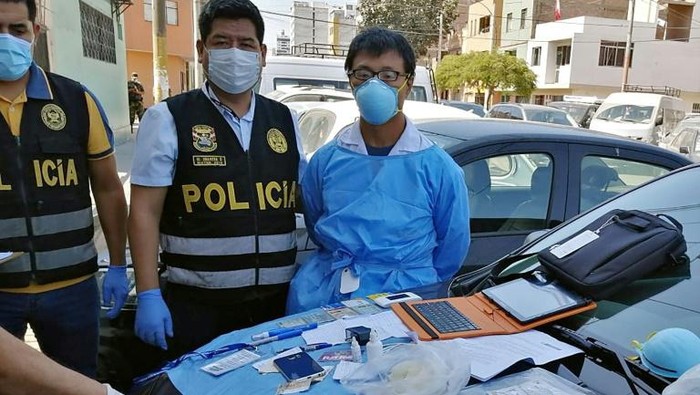 A Peruvian police photo showing Chinese citizen Zhang Tianxing (R) after his arrest for the unauthorized use of stolen COVID-19 tests in a street in Lima, on April 12, 2020