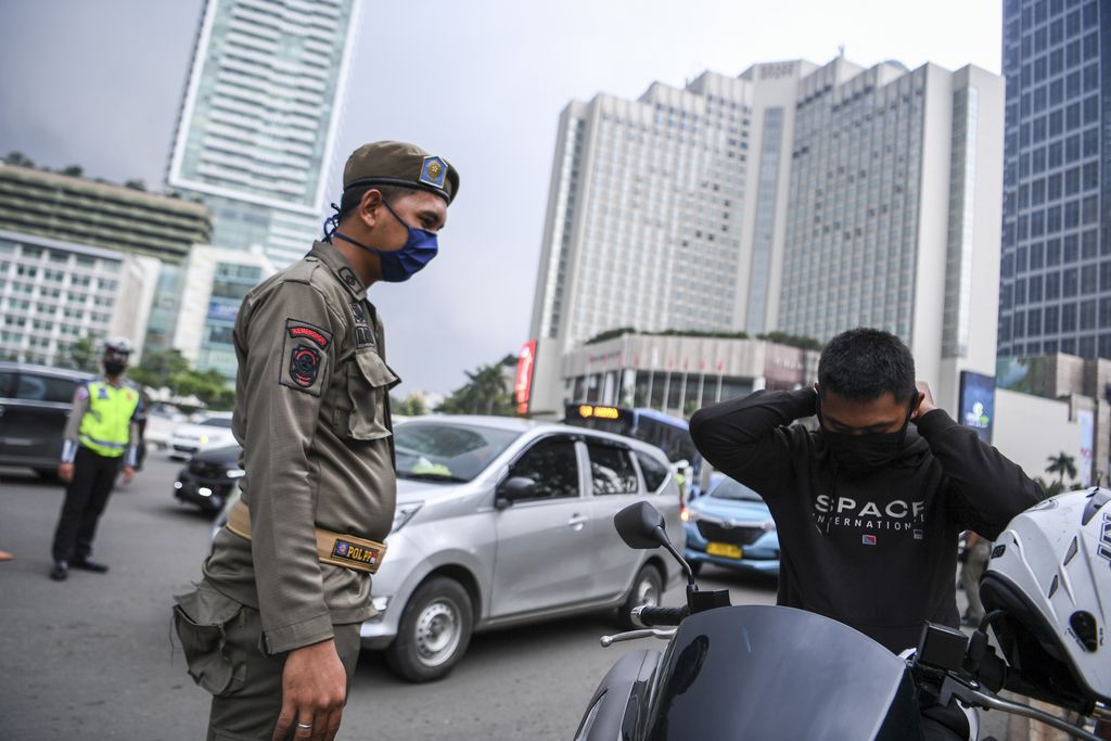 Satpol PP meminta pengendara motor mengenakan masker saat pemeriksaan kepatuhan Pembatasan Sosial Berskala Besar (PSBB) di kawasan Bundaran HI, Jakarta, Senin (13/4/2020). Pemeriksaan tersebut untuk memastikan setiap pengendara mobil dan motor mematuhi aturan PSBB yang diterapkan di DKI Jakarta. ANTARA FOTO/Hafidz Mubarak A/wsj.