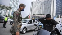 Petugas Satpol PP meminta pengendara motor untuk berhenti dan mengenakan masker saat pemeriksaan kepatuhan Pembatasan Sosial Berskala Besar (PSBB) di kawasan Bundaran HI, Jakarta, Senin (13/4/2020) sore.