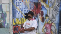 Seorang warga berolah raga dengan latar belakang mural ajakan melawan COVID-19 di Depok, Jawa Barat, Selasa (14/4/2020). ANTARA FOTO/Wahyu Putro A.