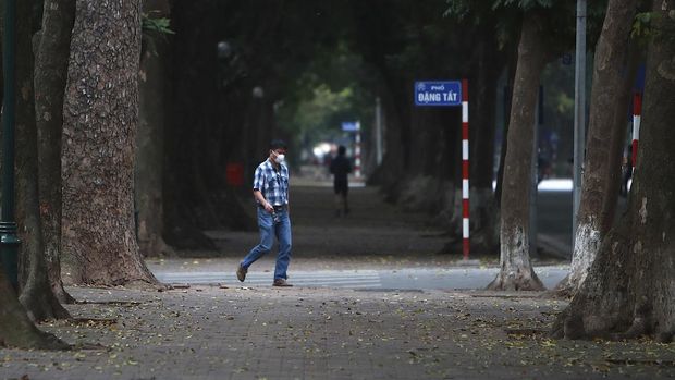 A man wearing a face mask walks on a quiet street in Hanoi, Vietnam, Wednesday, April 1, 2020. Vietnam on Wednesday starts two weeks of social distancing to contain the spread of COVID-19. The new coronavirus causes mild or moderate symptoms for most people, but for some, especially older adults and people with existing health problems, it can cause more severe illness or death. (AP Photo/Hau Dinh)