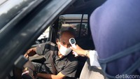 Petugas mengecek suhu tubuh pengendara mobil yang melintas di kawasan Pasar Sumber Arta, Kalimalang, Kota Bekasi, Jawa Barat.