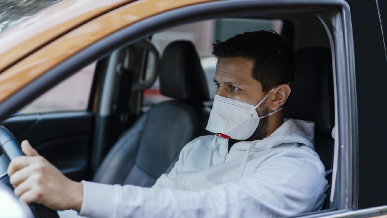 Naik mobil pakai masker Woman in protective mask driving a car on road. Safe traveling.
