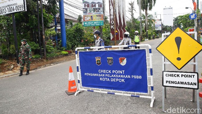 Petugas gabungan dari Dishub, Polisi dan TNI berjaga di kawasan Cinere yang merupakan perbatasan Kota Depok, Jawa Barat, Rabu (15/4/2020). Mulai hari ini Depok telah menerapkan pembatasan sosial berskala besar (PSBB)