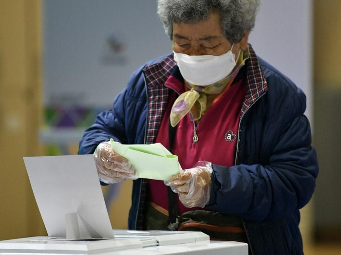 A South Korean woman casts her ballot for the parliamentary elections at a polling station in Seoul on April 15, 2020. - Temperature checks on voters, separate booths for those with fevers, special polling stations for the quarantined: South Koreans headed to the polls on April 15 with a big turnout expected despite the COVID-19 coronavirus threat. (Photo by Jung Yeon-je / AFP)