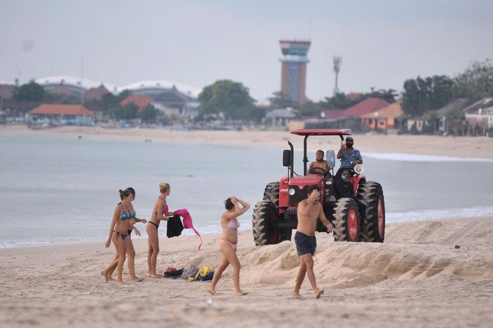 Petugas dengan traktor meminta wisatawan untuk meninggalkan kawasan pantai saat melakukan patroli di Pantai Kedonganan, Badung, Bali, Rabu (15/4/2020). Meskipun objek wisata tersebut telah ditutup sebagai upaya pencegahan penyebaran COVID-19, namun sejumlah wisatawan masih terpantau mengunjungi kawasan pantai dengan melanggar portal penutup maupun tanda pemberitahuan yang telah dipasang. ANTARA FOTO/Fikri Yusuf/foc.