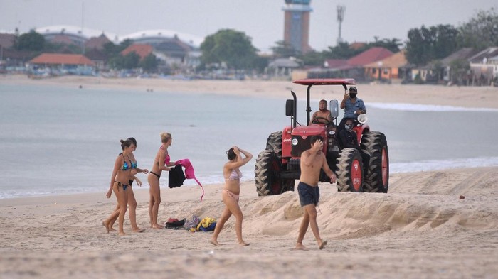 Petugas dengan traktor meminta wisatawan untuk meninggalkan kawasan pantai saat melakukan patroli di Pantai Kedonganan, Badung, Bali, Rabu (15/4/2020). Meskipun objek wisata tersebut telah ditutup sebagai upaya pencegahan penyebaran COVID-19, namun sejumlah wisatawan masih terpantau mengunjungi kawasan pantai dengan melanggar portal penutup maupun tanda pemberitahuan yang telah dipasang. ANTARA FOTO/Fikri Yusuf/foc.