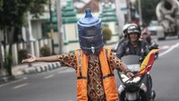 Seorang warga di kawasan Yogyakarta punya cara unik untuk melindungi diri dari penyebaran virus Corona. Ia mengenakan pelindung wajah dari galon bekas saat sedang bekerja mengatur lalu lintas di Jalan Tamansiswa, DI Yogyakarta. ANTARA FOTO/Hendra Nurdiyansyah.