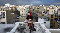 Mojgan Hosseini, anggota Orkestra Nasional Iran berusia 28 tahun, memainkan Qanun di atap rumahnya. 