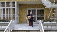 Musisi Ali Sarlak, bermain Gitar di halaman rumahnya.