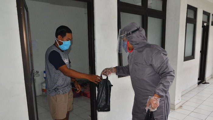 Petugas membagikan makanan kepada Orang Dalam Pemantauan (ODP) COVID-19 yang dikarantina di Rusunawa Bakalan Krapyak, Kudus, Jawa Tengah, Rabu (15/4/2020). Berbagai fasilitas diberikan pemerintah setempat kepada ODP yang sebagian besar para pemudik tersebut seperti kamar tidur dan kamar mandi pribadi, fasilitas kesehatan dan jaminan makan untuk kenyamanan ODP selama di karantina. ANTARA FOTO/Yusuf Nugroho/aww.