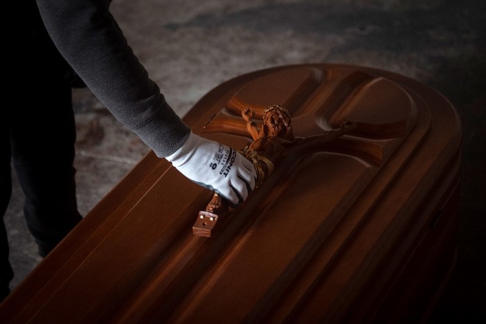 An employee puts a crucifix on a coffin at the Yago Gonzalez coffin-making factory in Pinor, northwestern Spain, on April 14, 2020. - The Galician town of Pinor in northern Spain has just 1,100 inhabitants and a peculiarity--it has nine casket factories, which have doubled their production with the coronavirus pandemic. (Photo by MIGUEL RIOPA / AFP)
