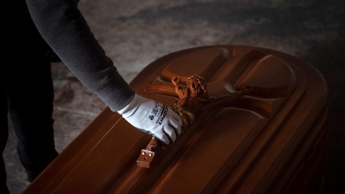 An employee puts a crucifix on a coffin at the Yago Gonzalez coffin-making factory in Pinor, northwestern Spain, on April 14, 2020. - The Galician town of Pinor in northern Spain has just 1,100 inhabitants and a peculiarity--it has nine casket factories, which have doubled their production with the coronavirus pandemic. (Photo by MIGUEL RIOPA / AFP)