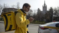 Sergei Nochovnyy mengantarkan makanan kepada warga dengan latar belakang gedung-gedung di Moskow, Rusia.