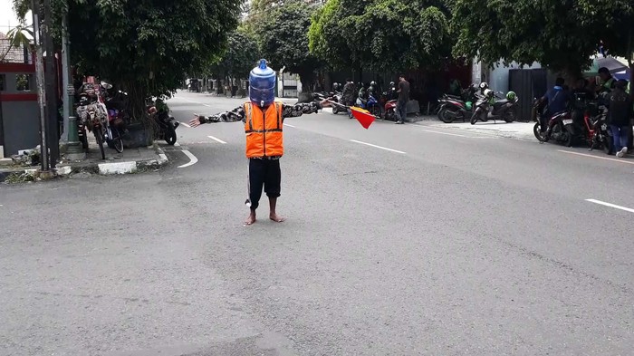 Bukan Masker, Pria Ini Pakai Galon untuk Tangkal Corona Kocak, pengatur lalu lintas di Yogyakarta, ini memakai galon air untuk menangkal virus Corona. Begini aksinya.