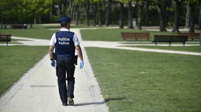 A police officer wearing protective gloves patrols in a park in Brussels on April 15, 2020 , as a strict lockdown has been in place for the past five weeks to stop the spread of COVID-19, the disease caused by the novel coronavirus. (Photo by JOHN THYS / AFP)