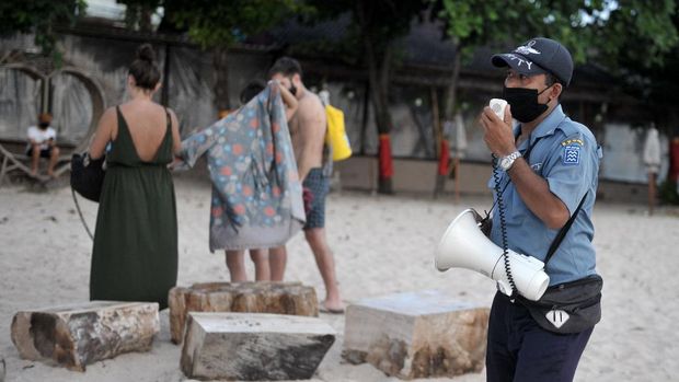 Petugas meminta wisatawan untuk meninggalkan kawasan pantai saat melakukan patroli di Pantai Kedonganan, Badung, Bali, Rabu (15/4/2020). Meskipun objek wisata tersebut telah ditutup sebagai upaya pencegahan penyebaran COVID-19, namun sejumlah wisatawan masih terpantau mengunjungi kawasan pantai dengan melanggar portal penutup maupun tanda pemberitahuan yang telah dipasang. ANTARA FOTO/Fikri Yusuf/foc.