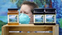Seorang petani menjual madu di pasar California pada 15 April. Menurut mereka pembatasan perjalanan di beberapa negara di Eropa membuat para petani kekurangan tenaga untuk panen. AP Photo/Marcio Jose Sanchez.
