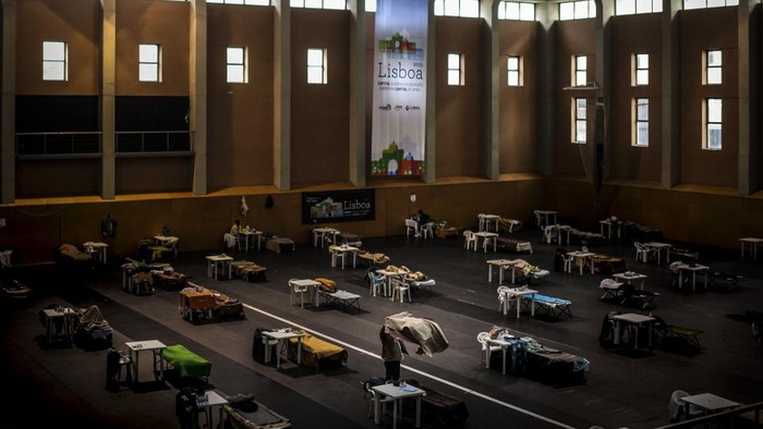 A man puts a blanket on his bed at the Casal Vistoso sports hall converted into a temporary shelter for the homeless as part of an emergency plan by the Lisbon city hall to mitigate the social impact of the coronavirus epidemic in Lisbon on April 14, 2020. - The city hall of Lisbon has created in recent weeks three food aid distribution points like this one, which provide more than 2,000 meals per day, and four temporary shelters installed in a gymnasium and a swimming pool, which currently host some 200 homeless people. (Photo by PATRICIA DE MELO MOREIRA / AFP)