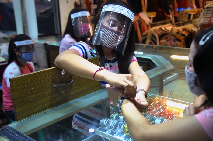 DI TOKO EMAS Pegawai toko menggunakan masker dan alat pelindung wajah (face shield) saat melayani pembeli di toko emas Rejeki, Pasar Bogor, Jawa Barat, Kamis (16/4/2020). Penggunaan alat pelindung wajah tersebut sebagai upaya pencegahan penyebaran wabah pandemi virus Corona (COVID-19). ANTARA FOTO/Arif Firmansyah /aww.