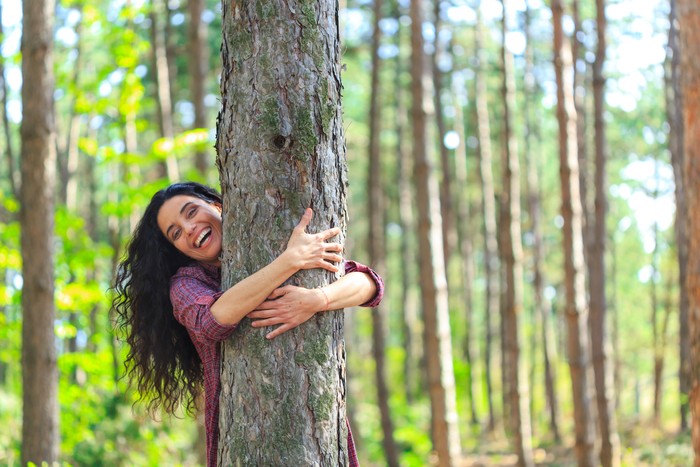 Gadis memeluk pohon besar di sebuah hutan.