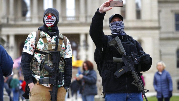 Para pendemo berunjuk rasa di depan balai kota Michigan, AS.  Mereka menentang aturan lockdown seperti tetap di rumah (stay at home) yang membuat pendemo khawatir terhadap pekerjaan dan pendapatan mereka. Aturan tersebut diberlakukan hingga 30 April mendatang.