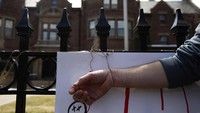 Salah satu peserta aksi mengikat tangannya di pagar sebagai simbol menolak dan menentang anjuran stay at home dari pemerintah setempat. Minnesota Public Radio via AP/Evan Frost.