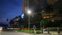Pejalan kaki tampak melintas di kawasan Bundaran Hotel Indonesia dengan latar belakang hotel yang menyalakan lampu membentuk gambar hati atau love.