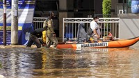 Warga melintasi banjir menggunakan perahu karet di Bukit Sawangan Indah, Depok.