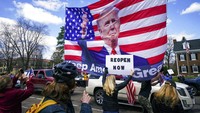 Pendemo juga mengibarkan bendera Amerika Serikat yang bergambar Donald Trump. Donald Trump sendiri telah menanggapi aksi-aksi demo tersebut. Trump terkesan menunjukkan dukungannya pada warga AS yang berdemo itu. Star Tribune via AP/Glen Stubbe.