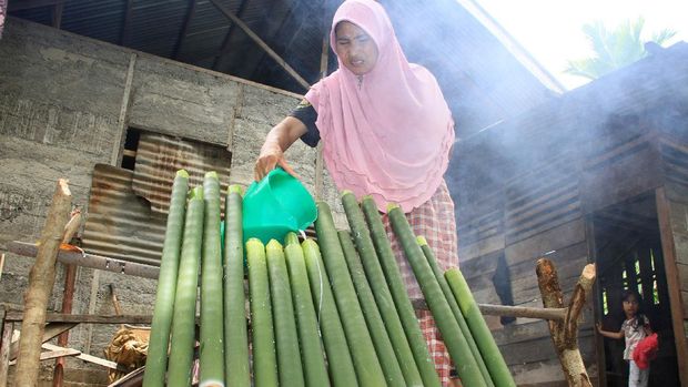 Warga memasukkan santan kelapa ke dalam bambu saat proses pembuatan lemang di Desa Alue Raya, Samatiga, Aceh Barat, Aceh, Sabtu (18/4/2020). Tradisi memasak dan membuat lemang bambu yang dilakukan secara turun temurun tersebut dilakukan dalam rangka menyambut bulan suci Ramadhan, kemudian lemang tersebut dibagikan kepada warga sekitar untuk mempererat silaturahim. ANTARA FOTO/Syifa Yulinnas/wsj.